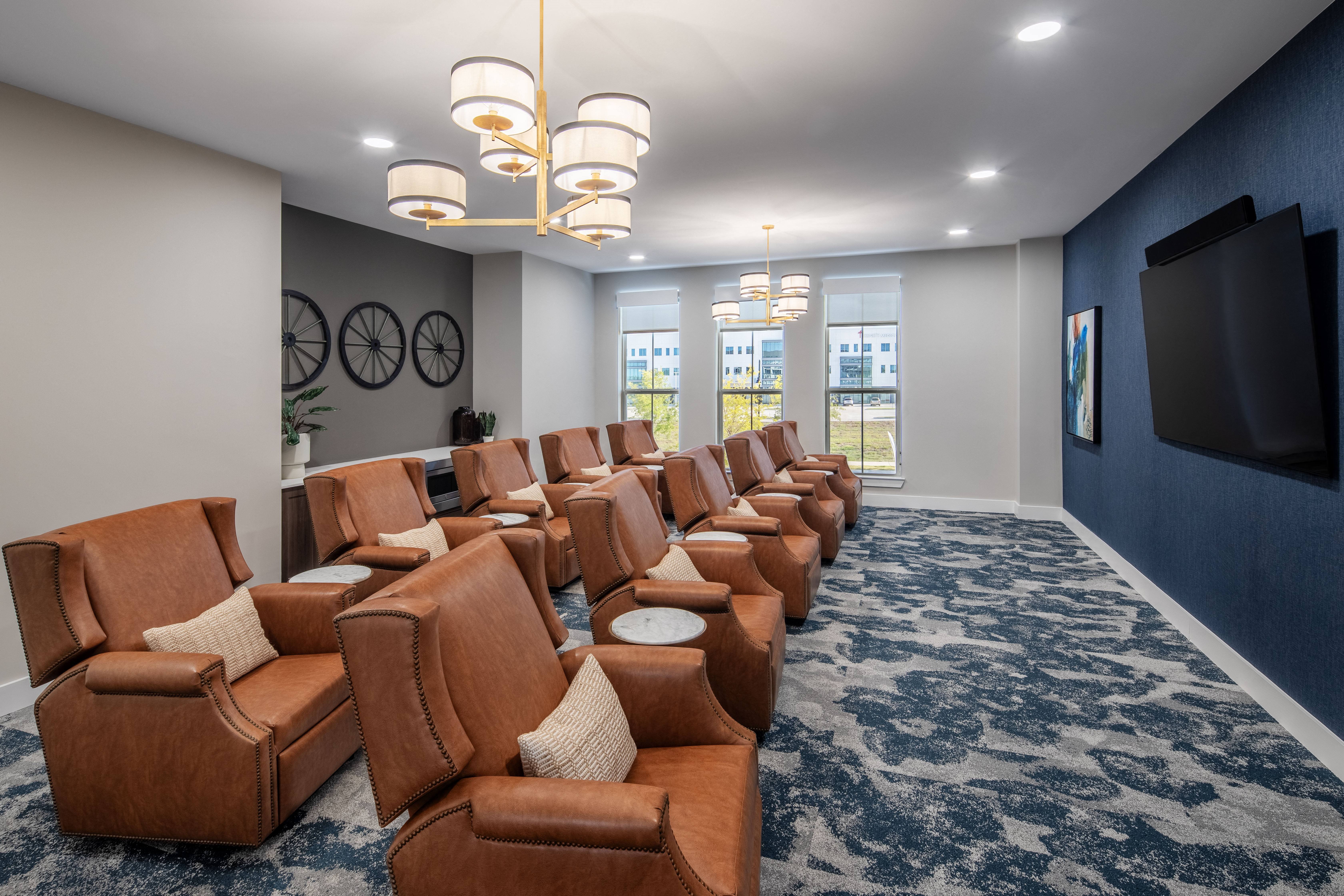 a large screening room with leather chairs and a tv at a senior apartment community